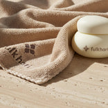 White container with 'fulkhari' branding on a beige towel on a wooden surface