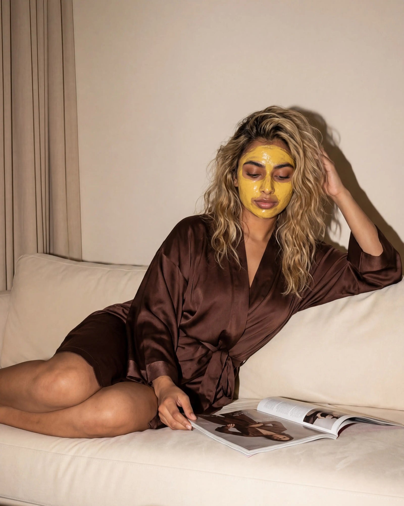 Woman relaxing on couch wearing Fulkhari hydrating Multani Mitti clay mask for self care