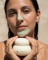 Model applying the cooling green Multani Mitti clay mask to her chin to target excess oil and impurities.