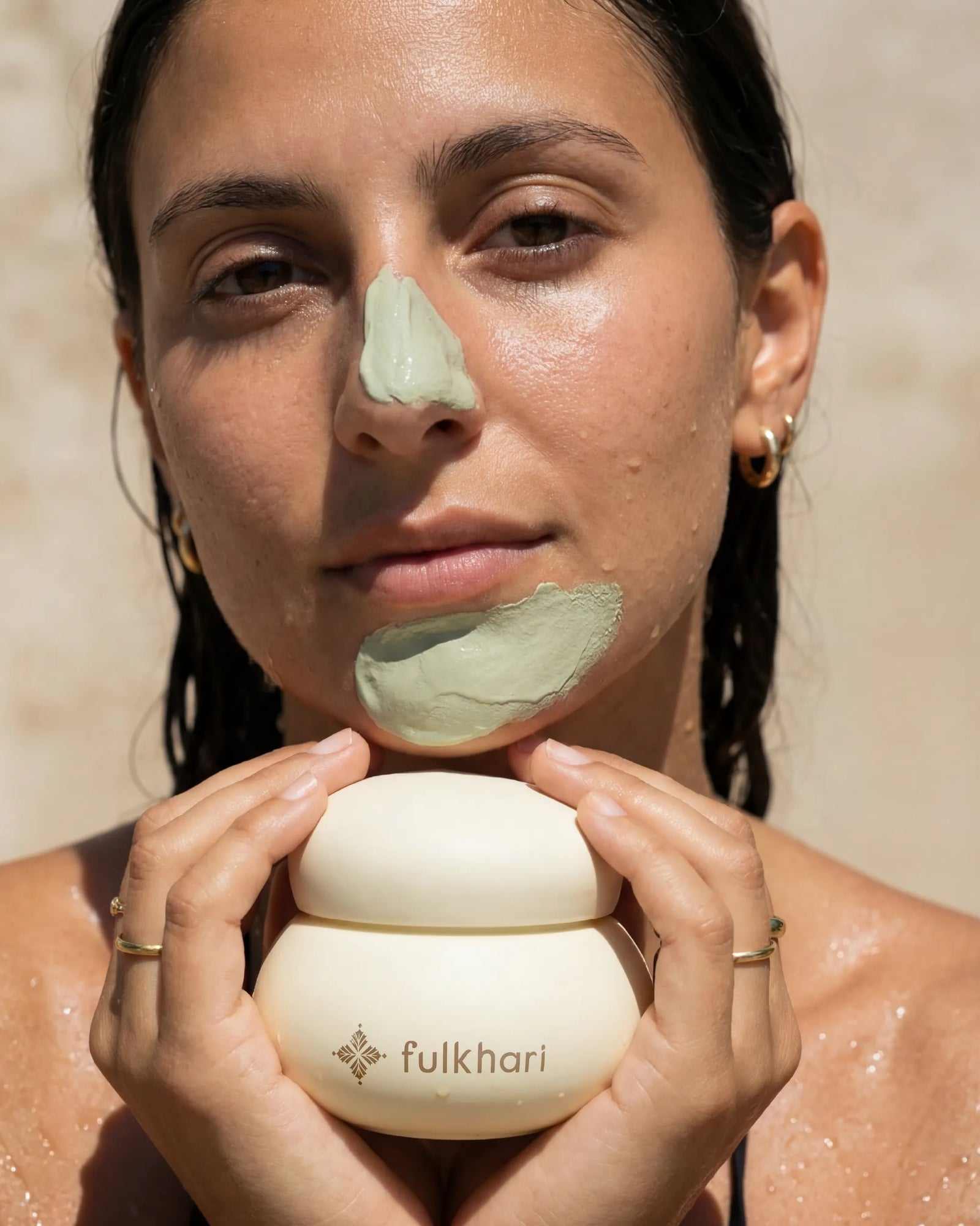 Model applying the cooling green Multani Mitti clay mask to her chin to target excess oil and impurities.