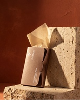 Fulkhari Facial Beauty Paper booklet made of eco-friendly kraft paper sitting on beige travertine stone, premium oil blotting sheets for instant shine control.