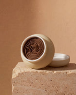 Open jar revealing the textured, earthy brown Multani Mitti paste rich in exfoliating botanicals.