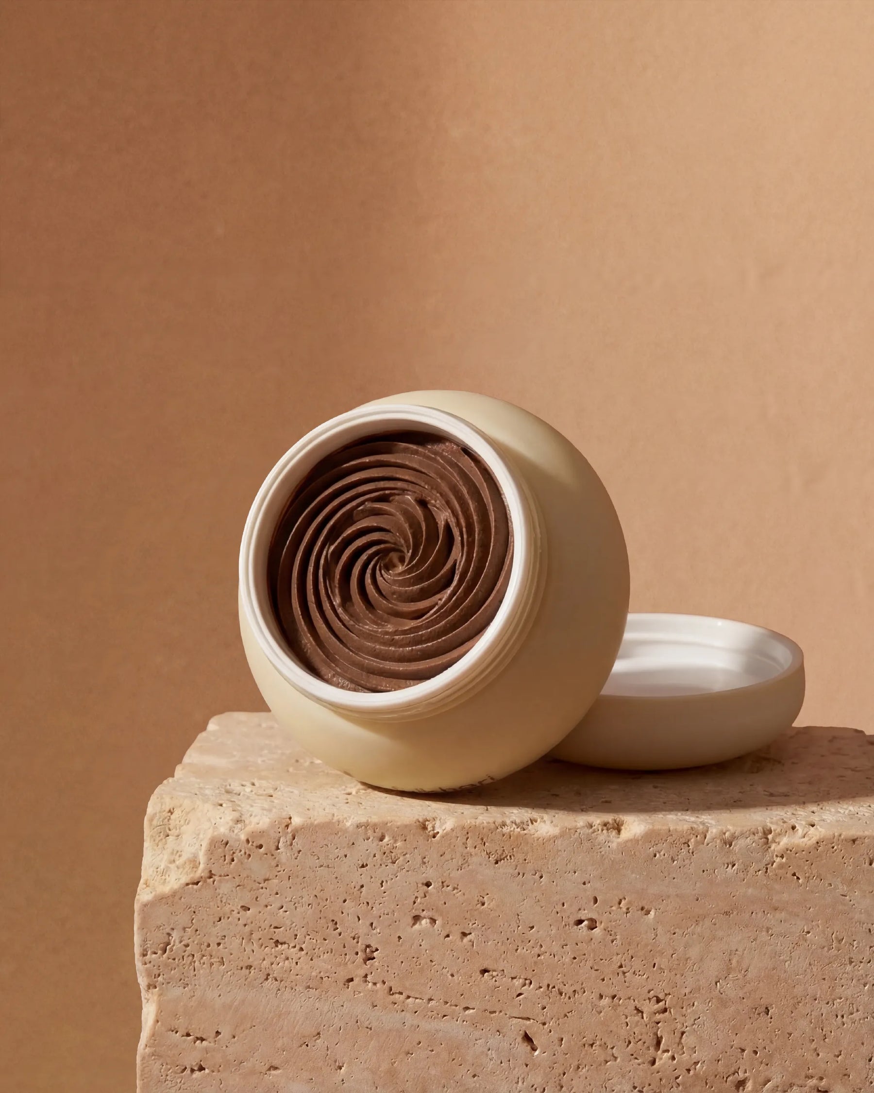 Open jar revealing the textured, earthy brown Multani Mitti paste rich in exfoliating botanicals.