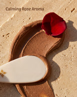 Exfoliating smear of reddish-brown Fuller's Earth clay with a rose petal and white applicator.