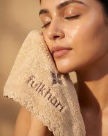 Model with glowing skin gently patting her face dry with the Fulkhari TerraPlush towel, a non-abrasive face cloth designed for sensitive skin.